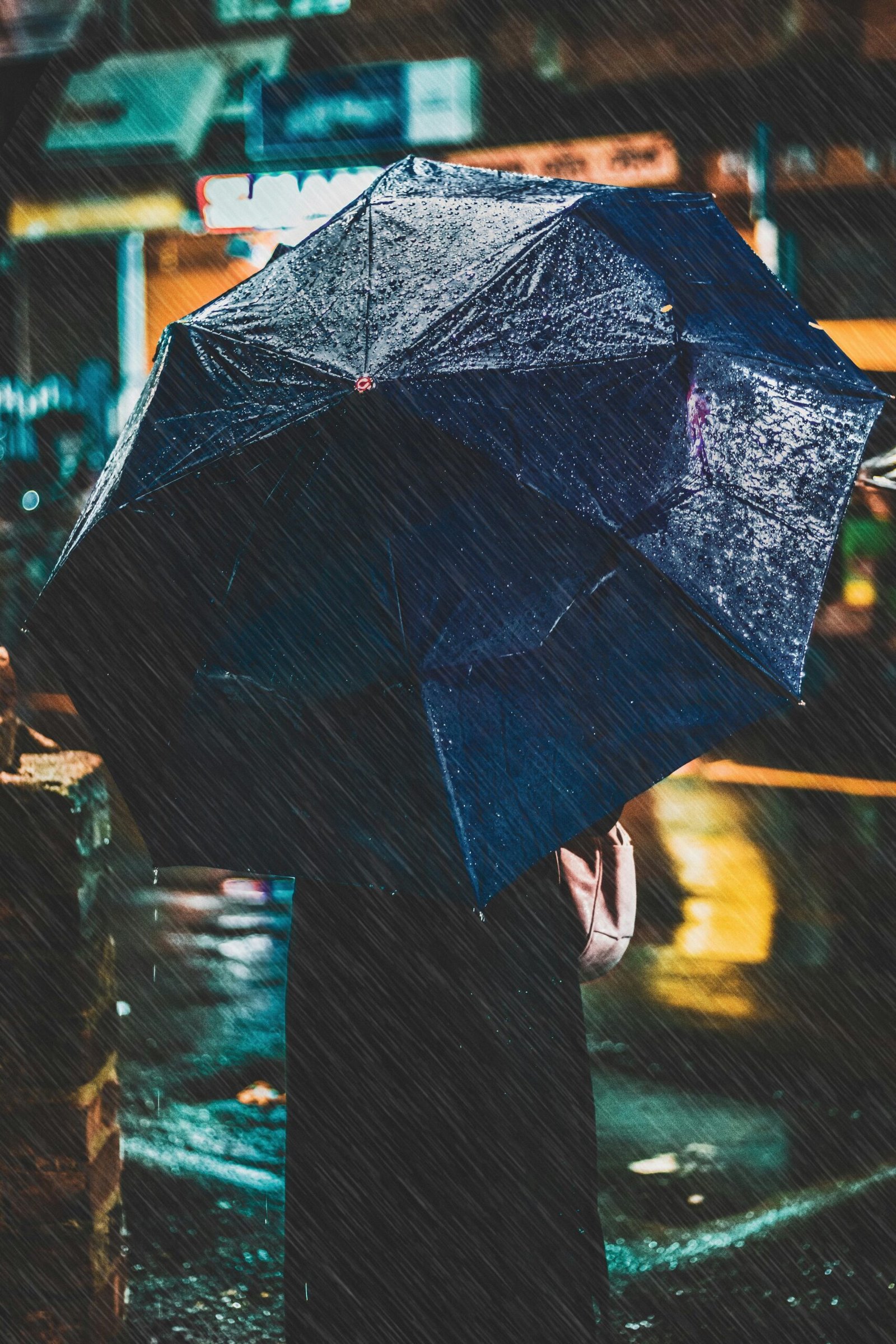 A person with an umbrella in rainy Kolkata evening, atmospheric and vibrant.