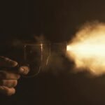 Close-up of a handgun firing with a bright flash in a dark setting, creating a dramatic effect.