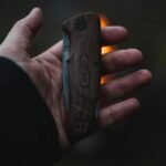 A person holds a wooden-handled folding knife outdoors, capturing a sense of adventure.