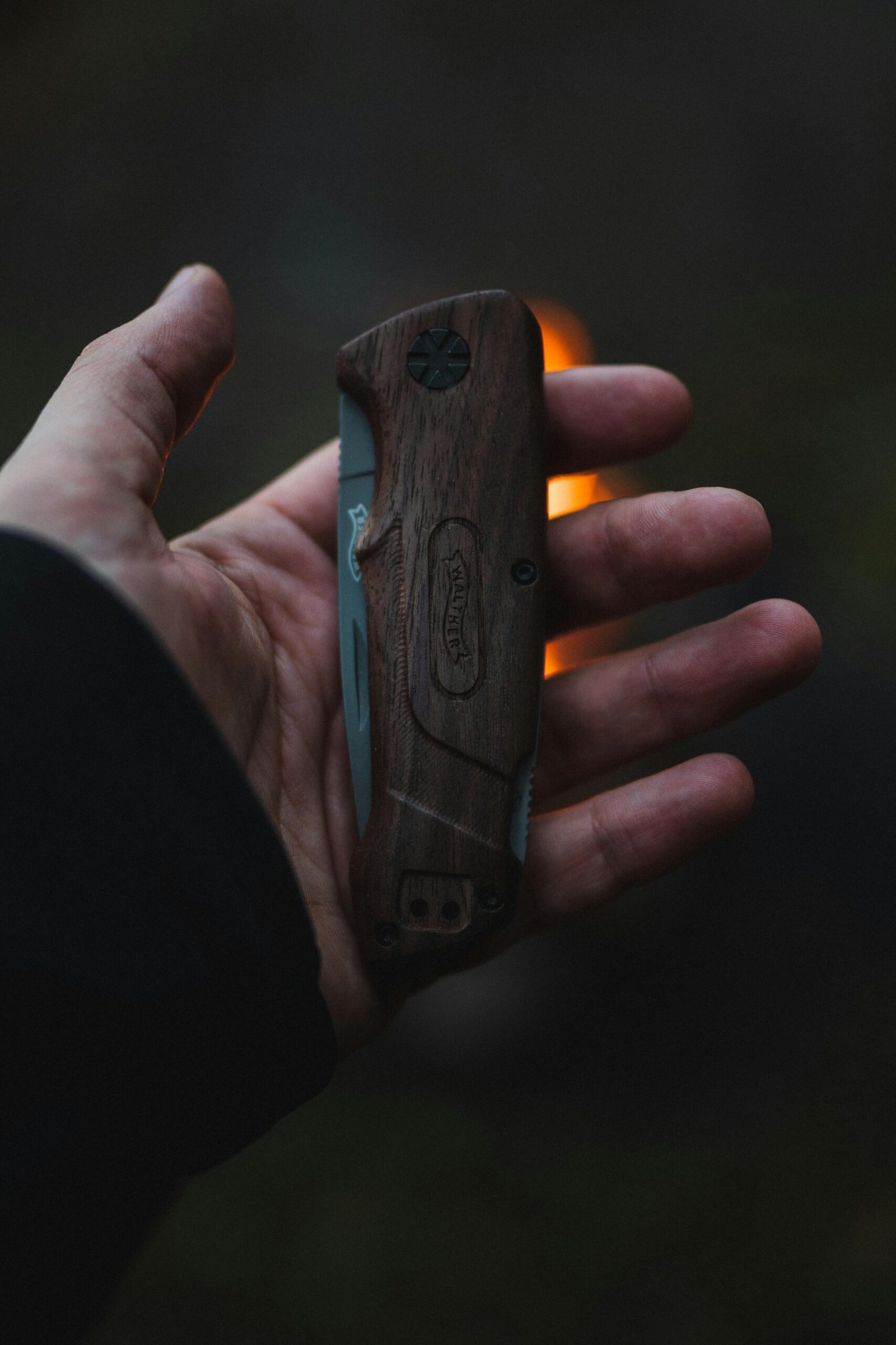 A person holds a wooden-handled folding knife outdoors, capturing a sense of adventure.