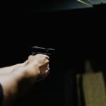 Arm aiming a handgun in a dark environment, showcasing focus and control.